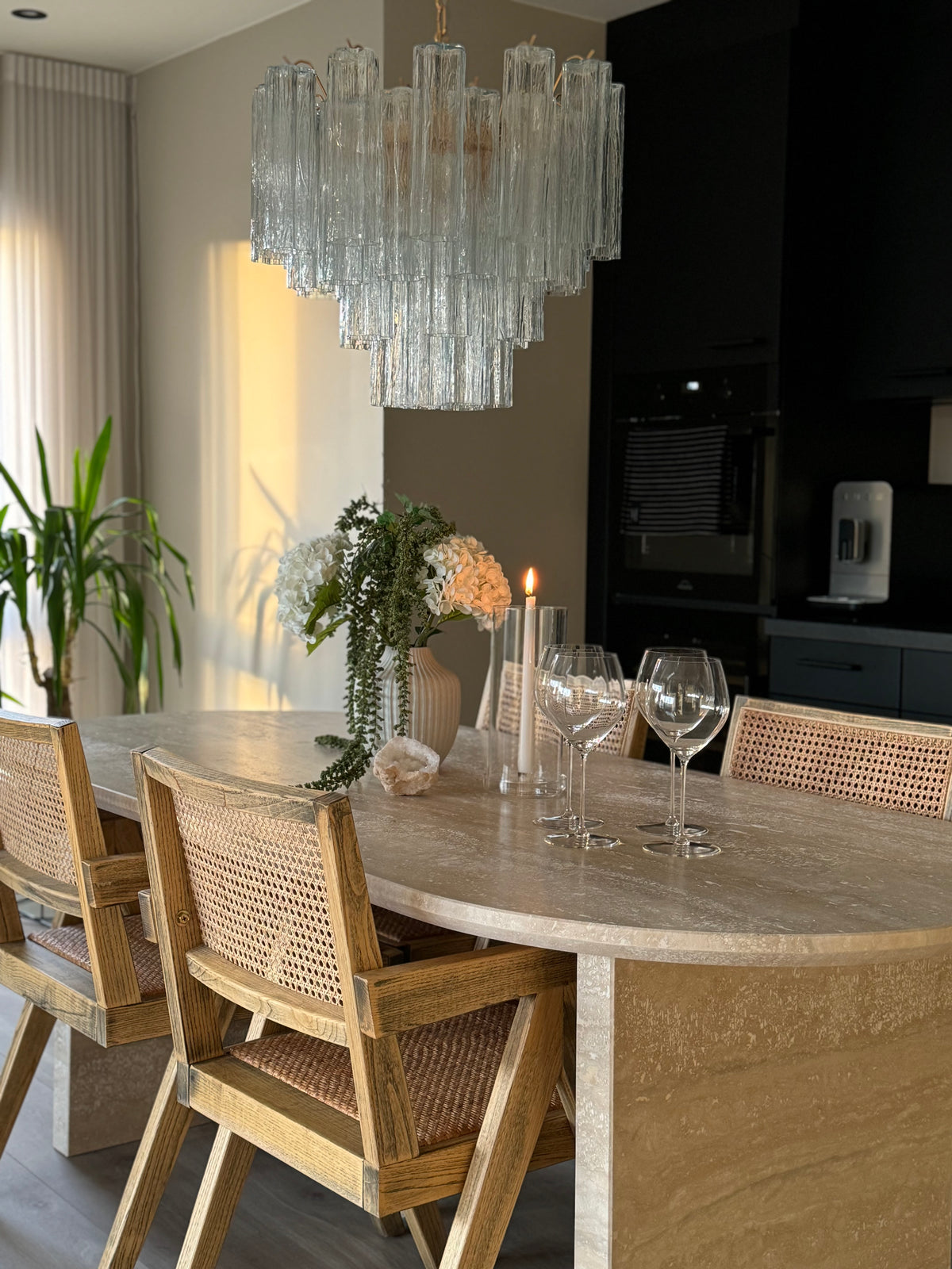 Chandelier with clear glass tubes over a travertine dining table