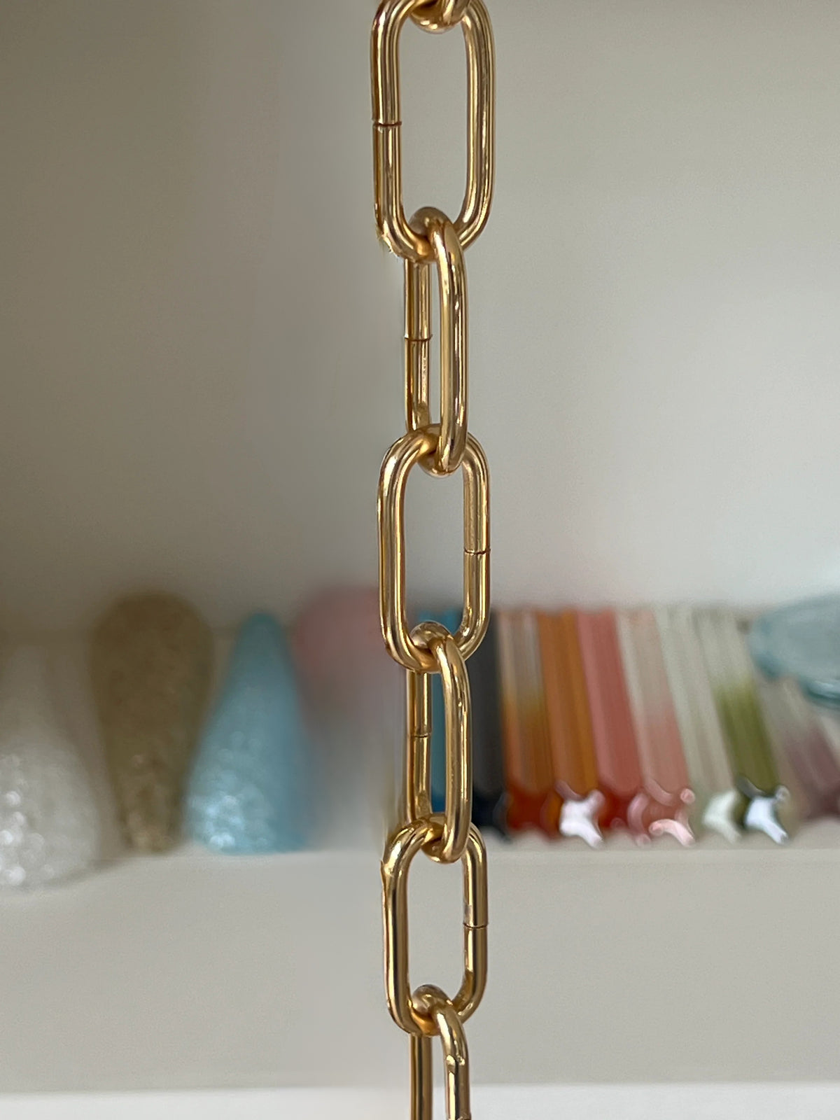 Close-up of a polished gold chain in front of coloured glass